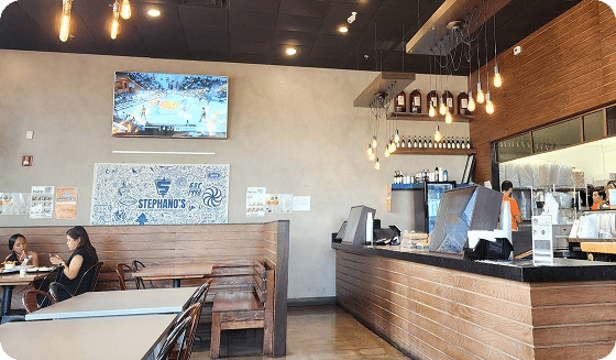 Locations 6 A restaurant interior with a TV showing basketball, a "STEPHANO'S" sign, and a counter with staff.