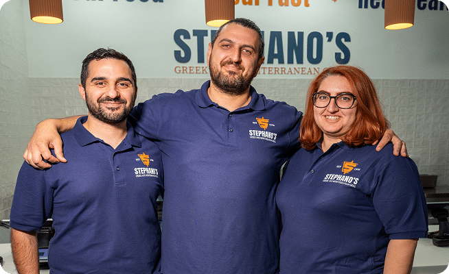 Three smiling people in blue "STEPHANO'S" polo shirts stand with arms around each other.